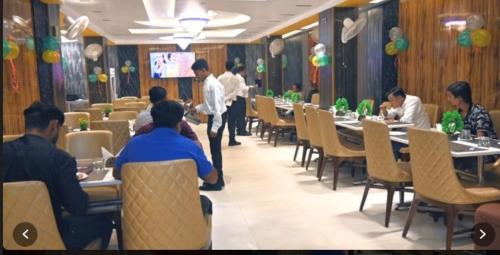 eine Gruppe von Personen, die in einem Restaurant an Tischen sitzen in der Unterkunft Hotel Five Star Inn By BookingCare in Muzaffarpur