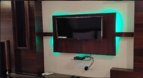 Hotel Five Star Inn By BookingCare في مظفربور: تلفزيون بشاشة مسطحة على جدار مع ضوء أخضر