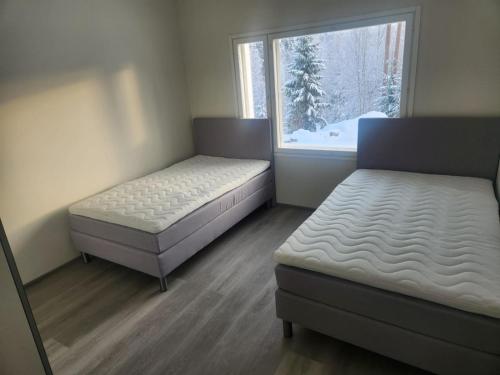 拉赫蒂的住宿－Uusi huvila Lahdessa，一间带两张床的卧室和一个带雪的窗户。