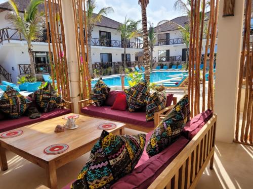 um pátio com uma mesa e cadeiras e uma piscina em Sand Beach Boutique Hotel em Bwejuu