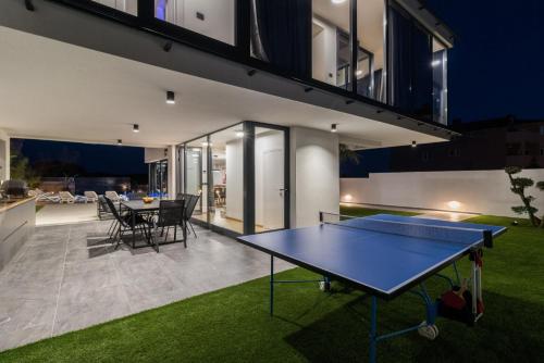 a ping pong table in the backyard of a house at Villa Miaa newly built modern villa in Medulin for 9 people with heated swimming pool & jacuzzi in Medulin
