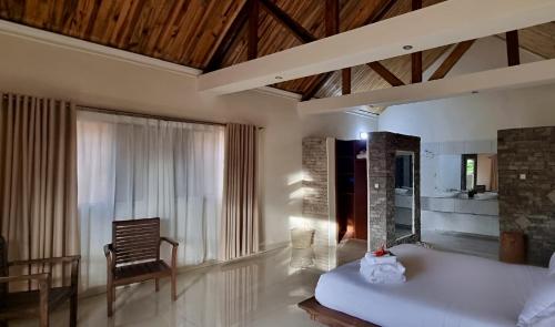 ein Schlafzimmer mit einem Bett und einem Stuhl in einem Zimmer in der Unterkunft Mahafaly Hotel & Resort in Antsirabe