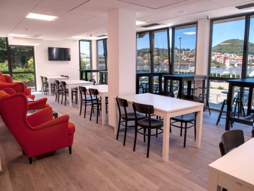 a waiting room with tables and chairs and windows at Hostel Sol in Dubrovnik