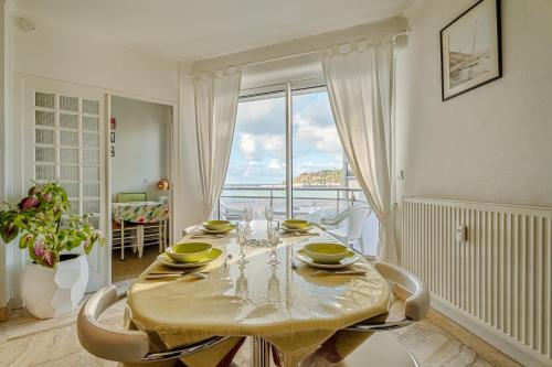 une salle à manger avec une table et une grande fenêtre dans l'établissement Appartement Le Rial - Erquy, à Erquy