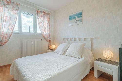 um quarto com uma cama branca e uma janela em Appartement Le Rial - Erquy em Erquy