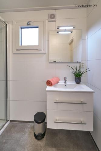 a white bathroom with a sink and a mirror at Camping de Vinkenkamp in Lieren