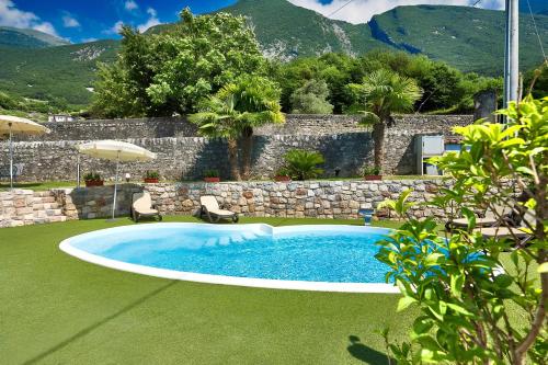 a pool in a yard with two chairs and an umbrella at Luxury Apartment Val di Monte in Malcesine