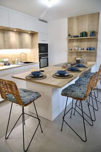 une cuisine avec un îlot doté de chaises et d'un comptoir dans l'établissement Paradis Bleu - Vue Lac avec Terrasse & Garage, à Annecy