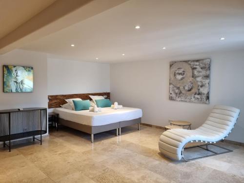 a bedroom with a white bed and a chair at Les Garrigues de la Vallée des Baux in Paradou