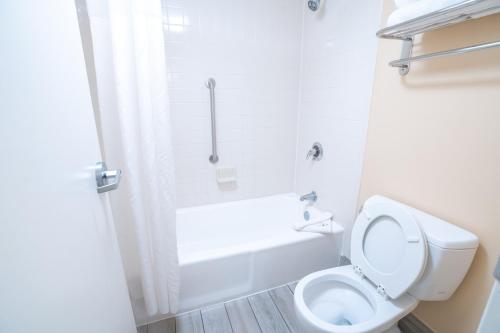 a white bathroom with a toilet and a bath tub at Quality Inn Palm Beach International Airport in West Palm Beach