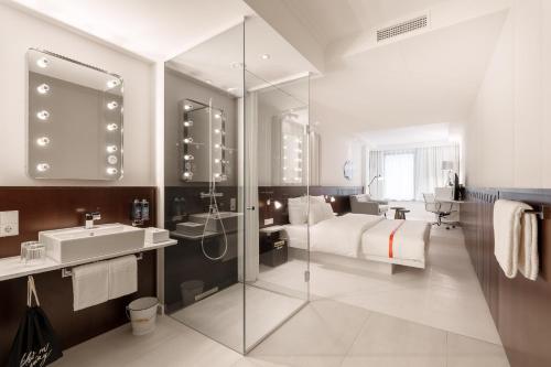 a bathroom with a bed and a shower and a sink at Ruby Hanna Hotel Stuttgart in Stuttgart