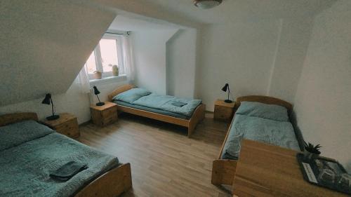 a room with two beds and a table and a window at Penzion Jizera Malá Skála in Malá Skála