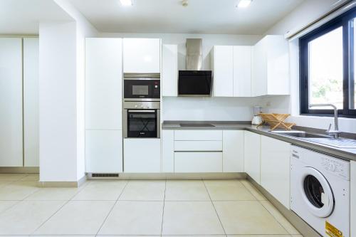 a white kitchen with white cabinets and a sink at Amazing Executive 2 Bedroom Available in Accra