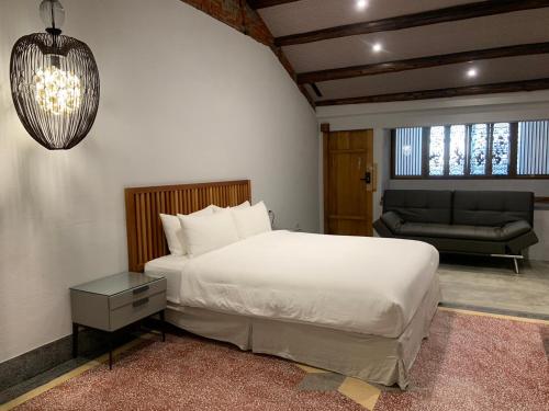a bedroom with a white bed and a couch at 璿 旅 Syuan Hotel in Tainan