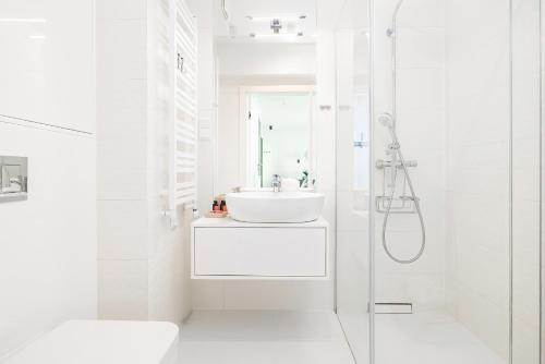 ein weißes Bad mit einem Waschbecken und einer Dusche in der Unterkunft Gryfa Pomorskiego Sea View Apartment with parking by Rent like home in Misdroy