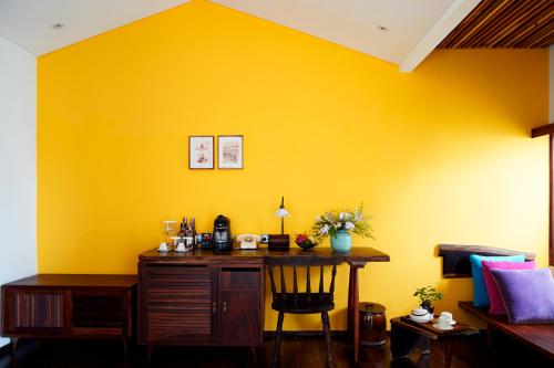 a yellow wall with a wooden desk in a room at The Myst Dong Khoi in Ho Chi Minh City