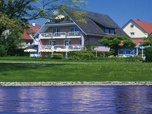 ein großes Haus am Ufer eines Wasserkörpers in der Unterkunft Hotel Strand-Café mit Gästehaus Charlotte in Langenargen