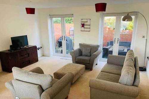 a living room with a couch and chairs and a tv at Balcony views + Parking in Lincolnshire