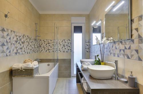 een badkamer met 2 wastafels, een bad en een tubermott bij Villa Una in Pula with heated pool and whirlpool in Pula