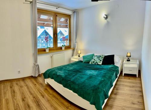een slaapkamer met een bed met een groene deken bij Apartament Morskie Oko ApartamentyZakopianskie Basen Sauna Jacuzzi in Zakopane