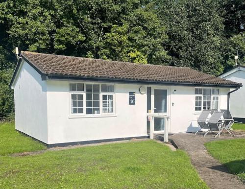a small white shed with two chairs in a yard at BumbleBee Lodge in Saint Cleer
