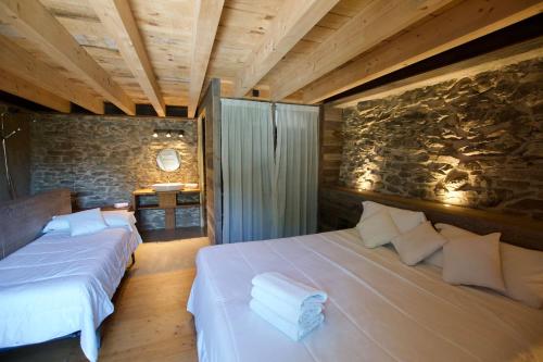 sypialnia z 2 łóżkami i kamienną ścianą w obiekcie Duplex Cal Josepo w mieście Ger