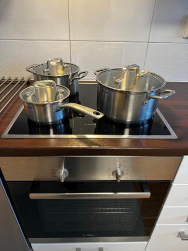 three pots sitting on top of a stove in a kitchen at Top floor flat with sauna, A/C & free parking in Vantaa