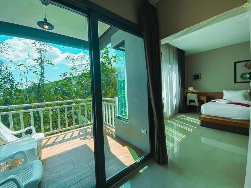 a bedroom with a balcony with a bed and a view at Bangnu Greenery Resort in Takua Thung