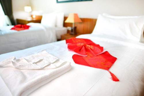 a hotel room with white towels and red flowers on a bed at Bangnu Greenery Resort in Takua Thung