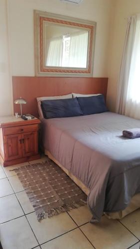 a bedroom with a bed and a table and a window at Apollo Guest House in Mahikeng