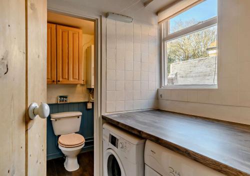 a bathroom with a toilet and a window at Bond Cottage in Overstrand