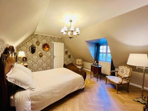 een slaapkamer met een bed, een lamp en een stoel bij Château le Withof in Bourbourg