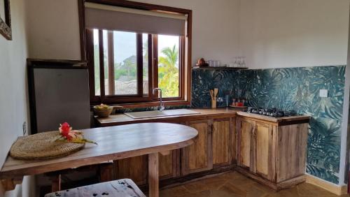 kuchnia z drewnianymi szafkami, umywalką i oknem w obiekcie Bantu Home w mieście Paje