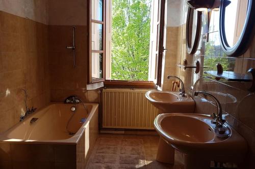 La salle de bains est pourvue de 2 lavabos, d'une baignoire et d'une fenêtre. dans l'établissement Maison de campagne avec jardin, à Montauban