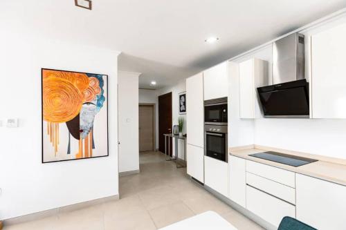 uma cozinha com armários brancos e uma pintura na parede em Premium One Bedroom Seaview Space Available em Acra