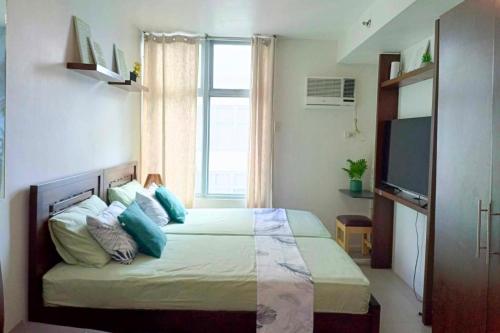um quarto com uma cama com almofadas azuis e uma janela em Fully-furnished Condo Accommodation in Makati em Manila