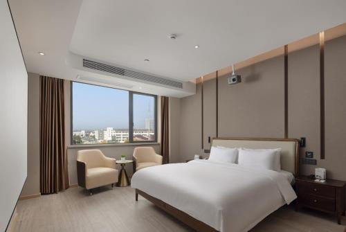 ein Schlafzimmer mit einem weißen Bett und einem großen Fenster in der Unterkunft Wanda Yue Suzhou Huangdai in Suzhou