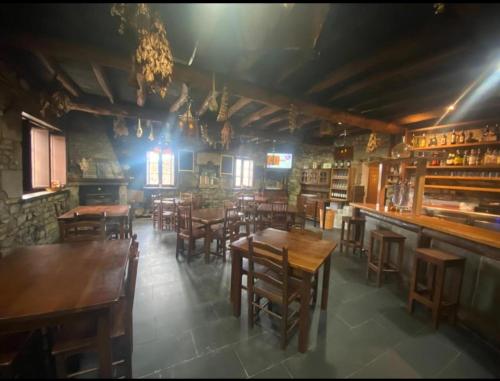 un restaurante con mesas y sillas de madera y un bar en Venta Celta, en O Cebrero