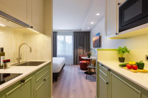 a kitchen with a sink and a room with a bed at Citadines Les Halles Paris in Paris