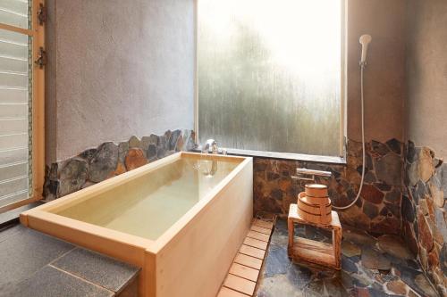 a large bath tub in a bathroom with rocks at Villa Noël Hakone Fuji Sauna&Open Air Bath in Hakone