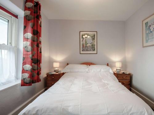 a bedroom with a large white bed with two night stands at 2 Bed in Aberdovey 80399 in Llwyngwril