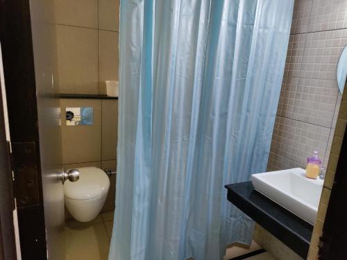 a bathroom with a toilet and a blue shower curtain at Private Room in villa in Bāgalūr