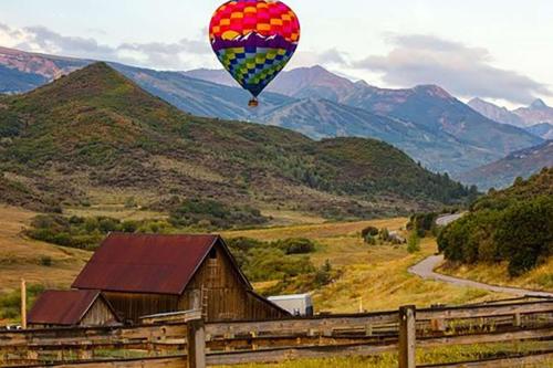 a hot air balloon flying over a field with a barn at Cottonwoods 1-D in Aspen