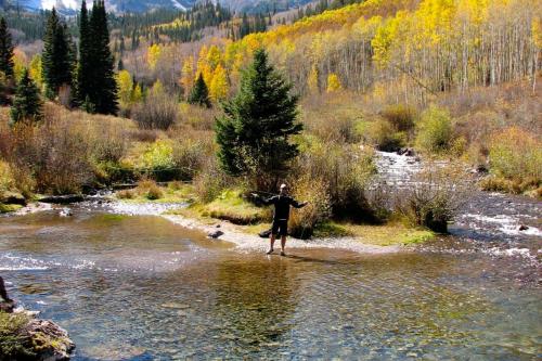 a man walking across a stream in a river at Cottonwoods 1-D in Aspen