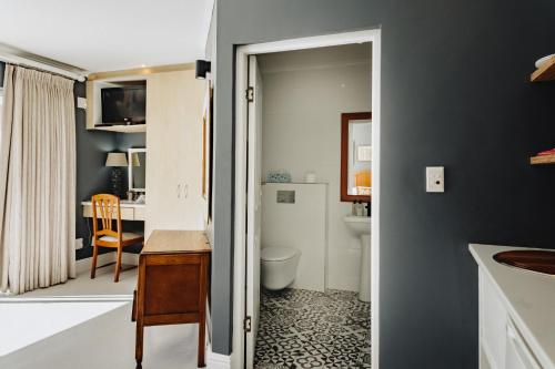 a bathroom with a sink and a toilet and a desk at Acorn Guest House in George