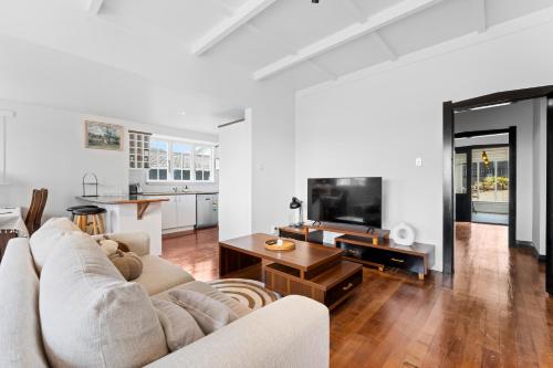 a white living room with a couch and a table at Albert.T Home in Auckland