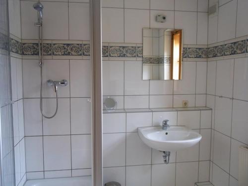 ein weiß gefliestes Bad mit einem Waschbecken und einer Dusche in der Unterkunft Ferienhaus Rentsch in Rudolstadt