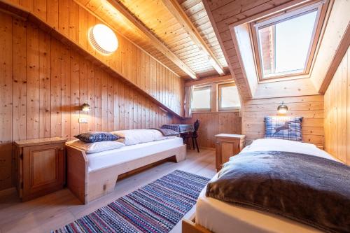 - une chambre avec 2 lits dans une cabane en bois dans l'établissement Panorama-Apartments Oberkofl, à Cadipietra