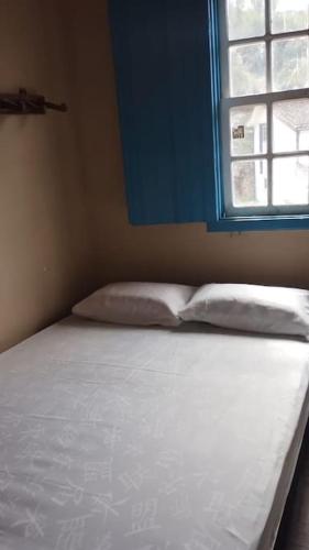 Bett in einem Zimmer mit blauem Fenster in der Unterkunft Casa Jabuticabeira in Ouro Preto