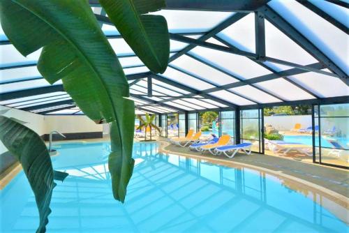 een groot zwembad met een glazen dak bij Maison Roche Blanche in Port Blanc